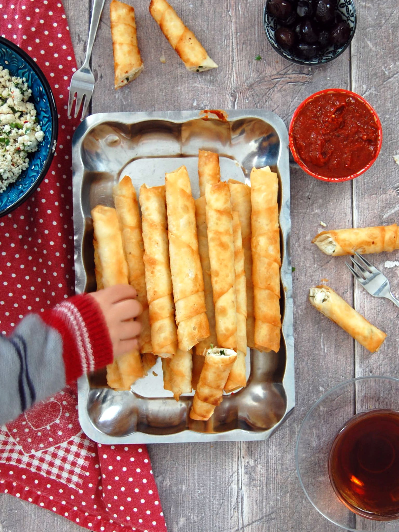 Childs hand grabbing Turkish cigar shapped fried pastries. Filled with cheese. Sigara borek