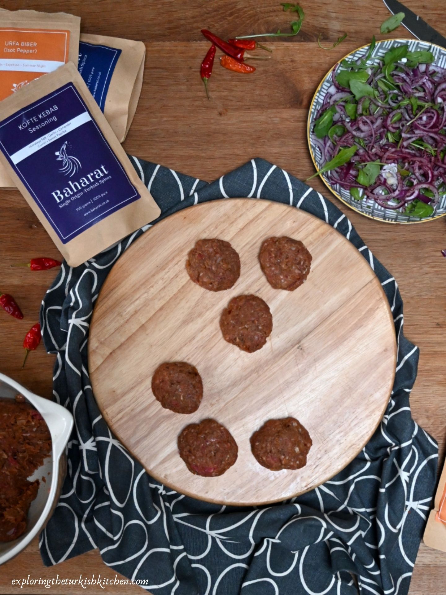Table with half made Turkish meatballs, sumac and red onions and packets of Turkish spices from Uk supplier Baharat.co.uk