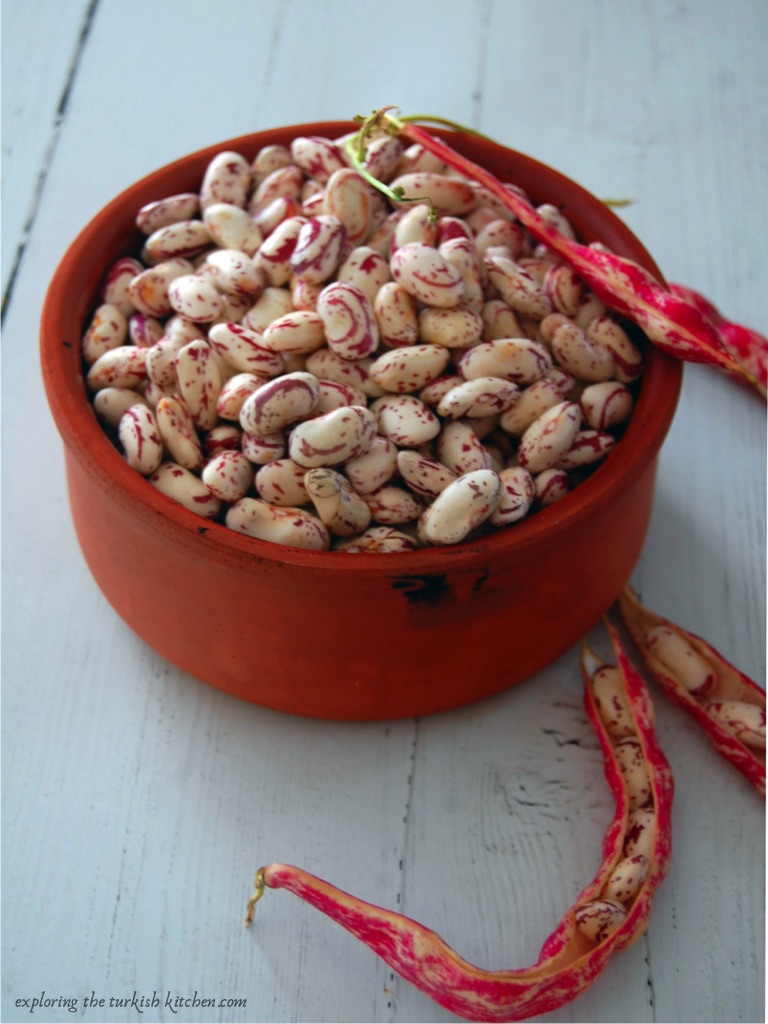 Traditional Turkish clay bowl holding summer beans, pink swirls on white beans. 