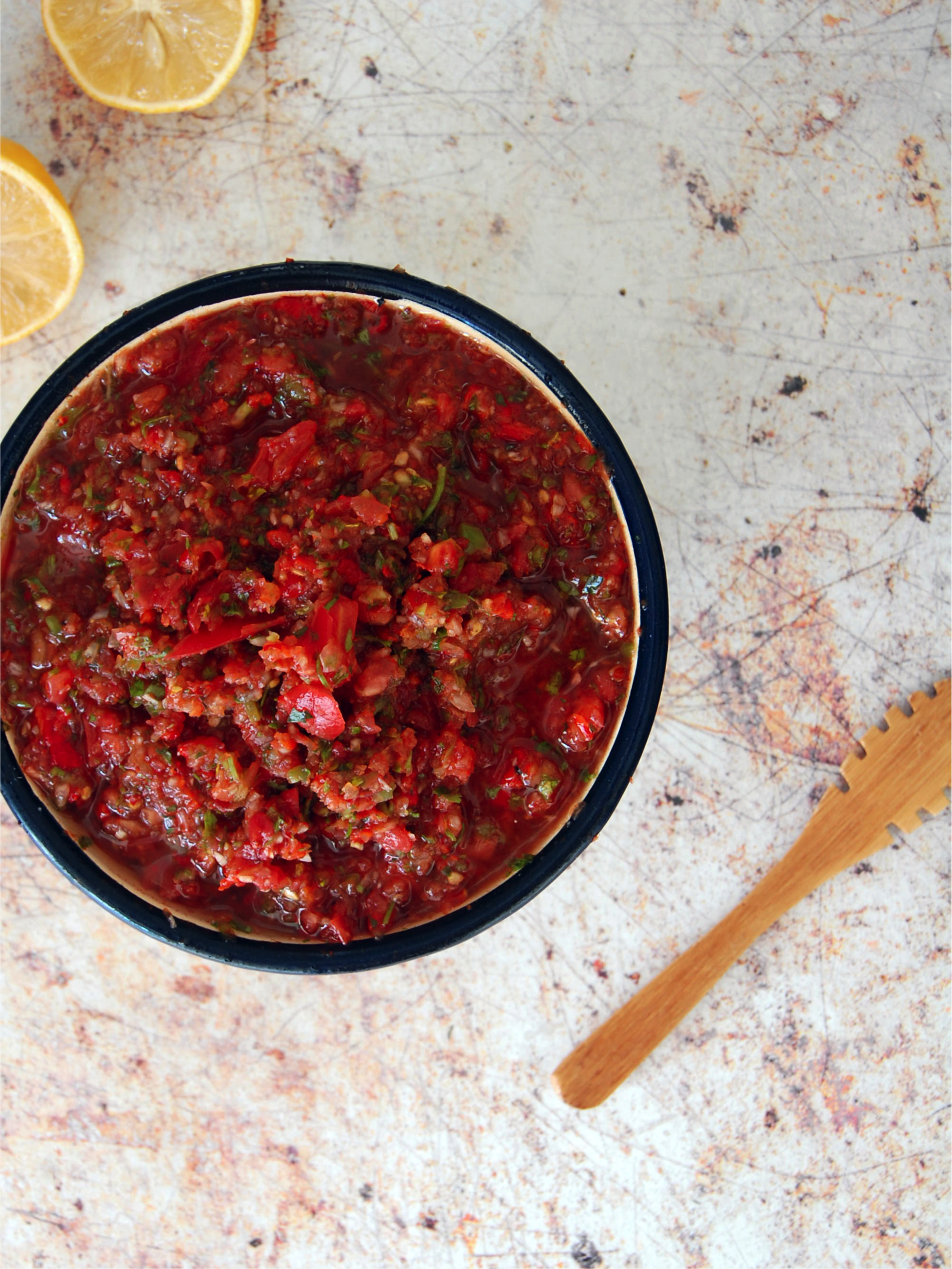Spicy Turkish Tomato salsa called ezme in an enamel bowl with cut lemons