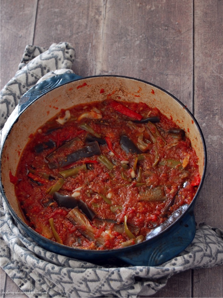 Cooked aubergine and tomatoes in a blueb cast iron dutch oven. Tomatoes reduced down into a suace ready to serve.