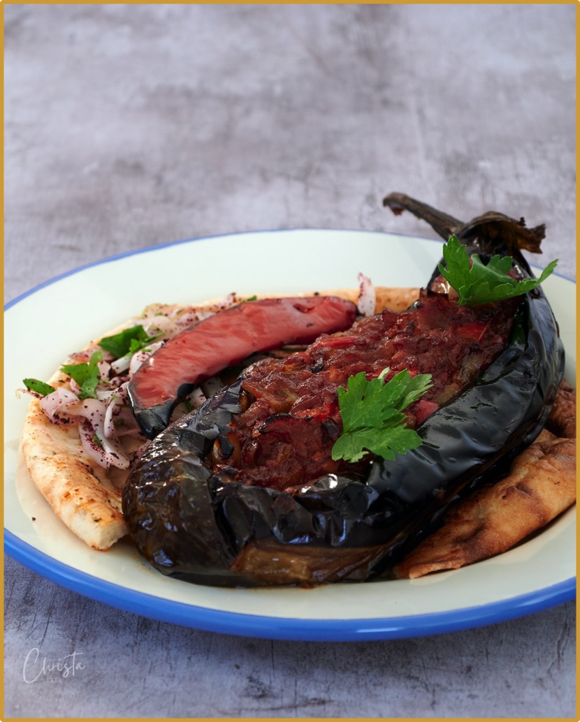 Plate with vegetable stuffed aubergine with onions, pide and chilli pepper. Imam bayıldı